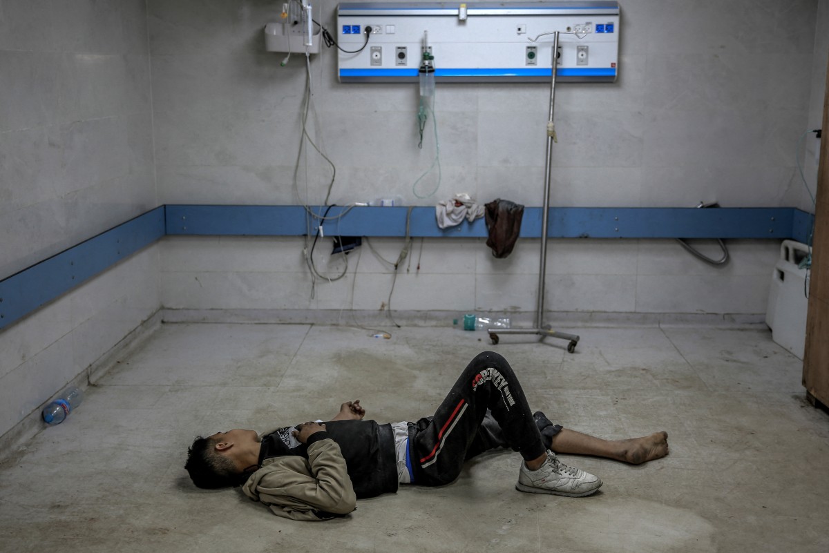 A young Palestinian man injured in Israeli bombardment lies on the ground as he awaits medical attention at the Al-Shifa hospital in Gaza City on March 15, 2024, amid the ongoing conflict between Israel and the Palestinian Hamas movement. (Photo by AFP)