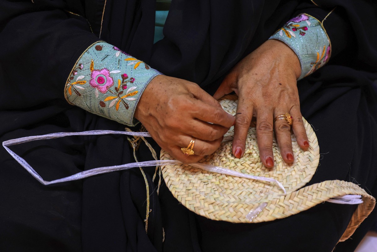 An Emirati woman weaves palm fronds during an annual heritage festival in Al-Ain on November 10, 2023. (Photo by Karim SAHIB / AFP)