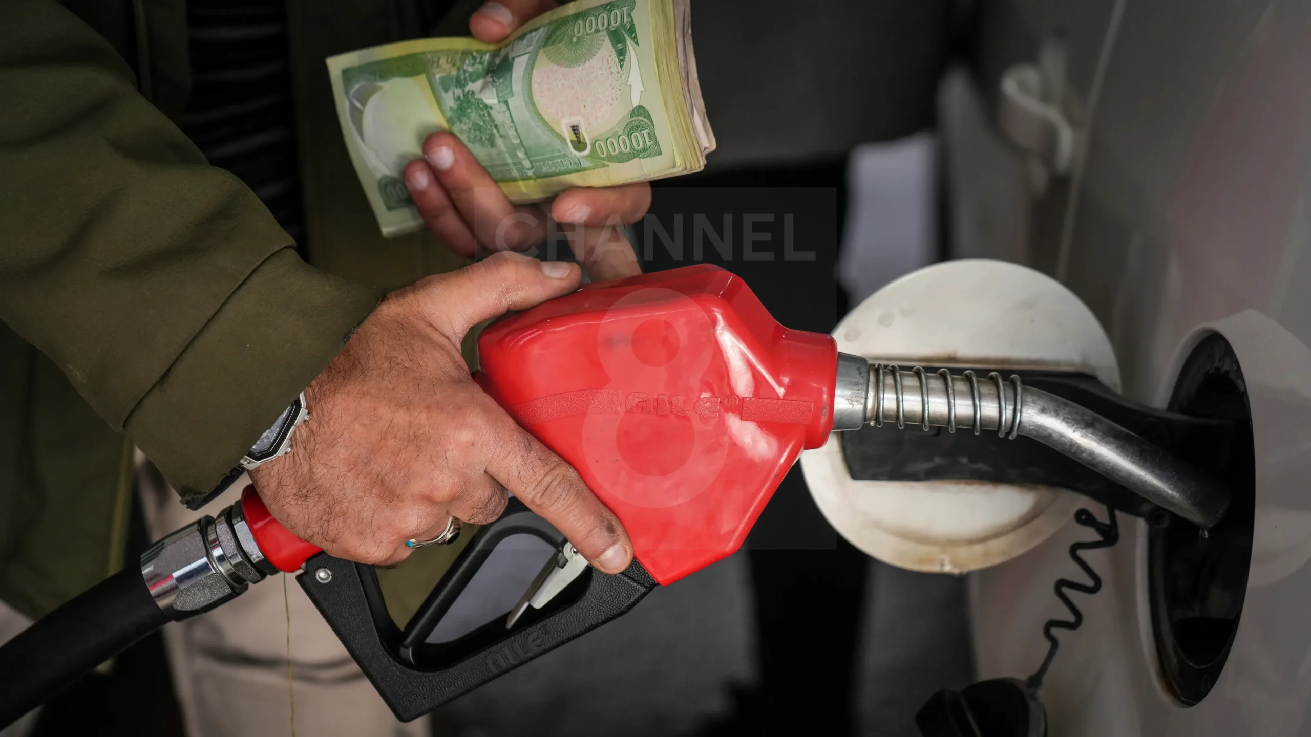 A man refuels a car while holding a stack of bills. Photo: Channel8