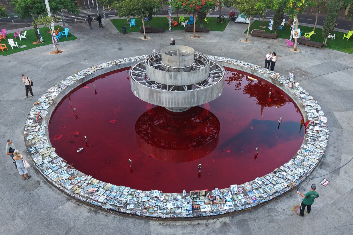 This aerial view shows people standing by the Dizengoff Fountain, filled with red dye in the Israeli coastal city of Tel Aviv on October 7, 2026, to mark the third anniversary of Hamas's October 7 attack.