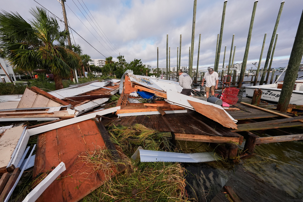 People retrieve belongings from a collapsed boat house in the aftermath of Hurricane Isaias in Destin, Fla., Saturday, Oct. 10, 2026. (AP Photo/Gerald Herbert)